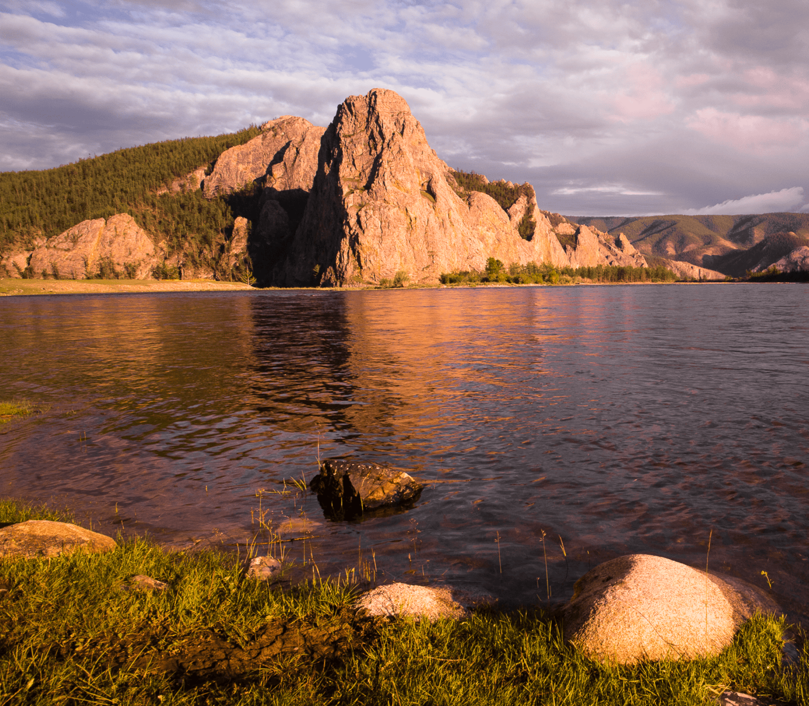 Golden-hour lake with rocky cliffs in northern Mongolia.